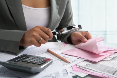 Businesswoman checking bills using magnifying glass clipart