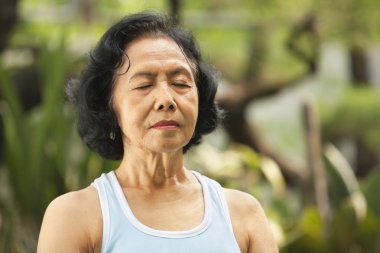 Close up of senoir woman meditating clipart