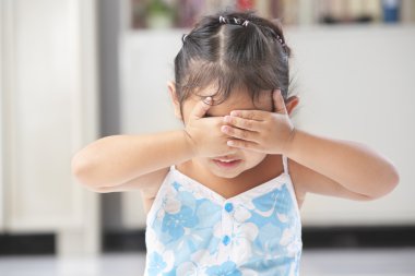 Little girl playing peekaboo or crying clipart