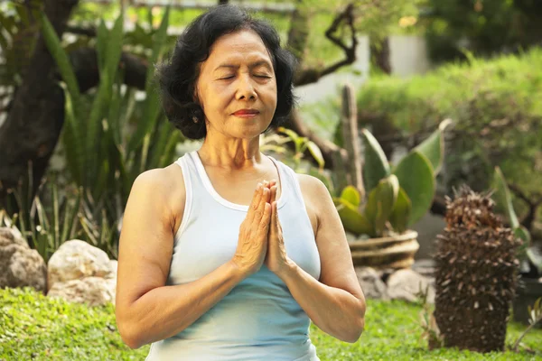 Азиатская старшая женщина медитирует для йоги снаружи — стоковое фото