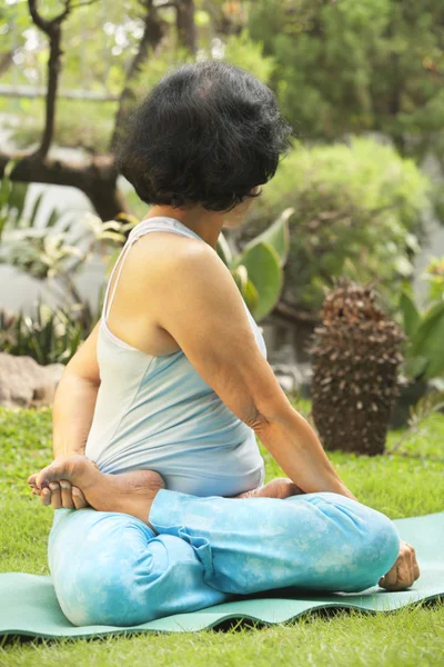 Äldre kvinna gör yoga på park — Stockfoto
