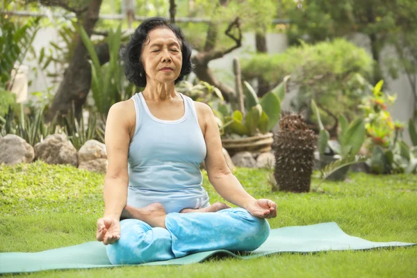 Asiática senior mujer meditando para yoga fuera —  Fotos de Stock