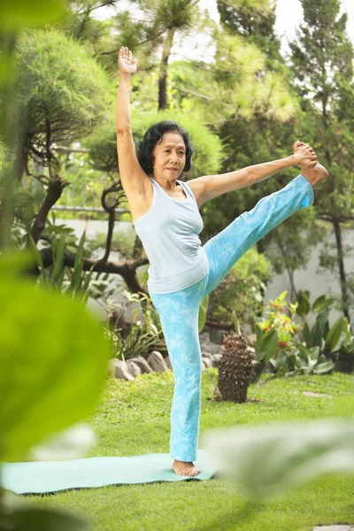 Äldre kvinna gör yoga på park — Stockfoto