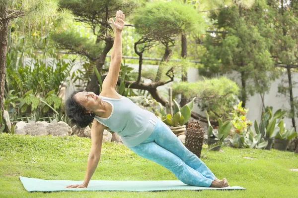 Äldre kvinna gör strecthing för yoga — Stockfoto