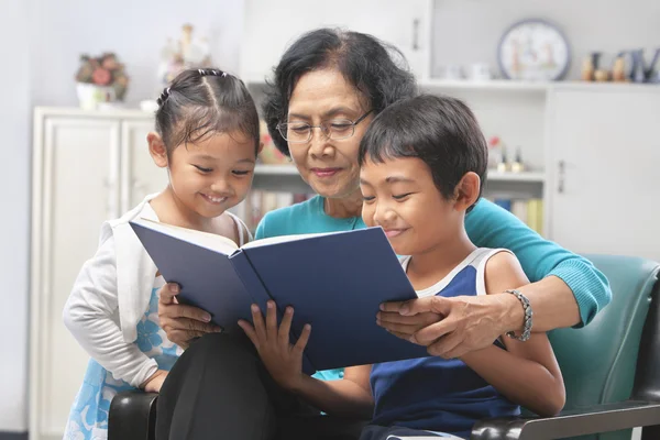 Abuela y nietos leyendo libro juntos — Foto de Stock