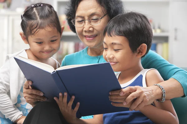 Grandma and grandchildren reading book together — Stock Photo, Image