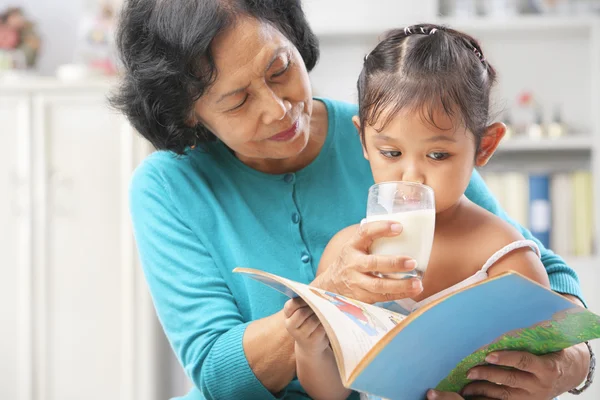 Grandma giving milk to her granddaugter — Stock Photo, Image