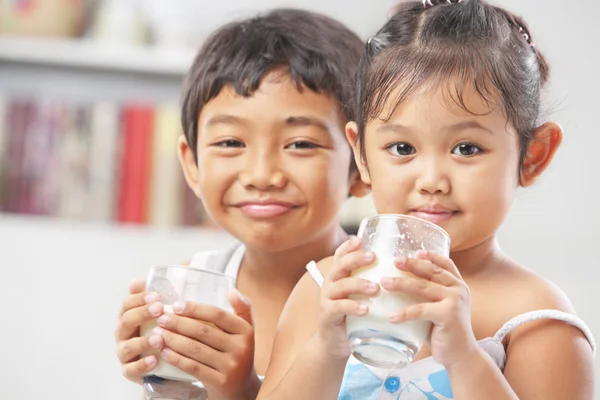 Dos niñas y niños cada uno sosteniendo un vaso de leche —  Fotos de Stock