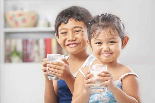 Due ragazzina e ragazzo ciascuno con un bicchiere di latte — Foto Stock