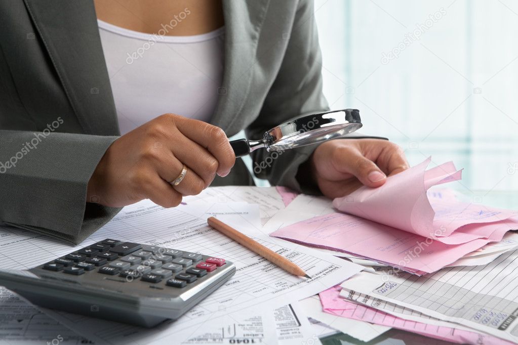 Businesswoman checking bills using magnifying glass