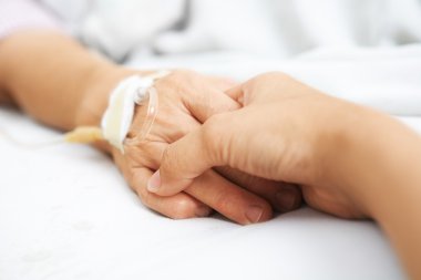 Daughter holding her mother hand in hospital clipart