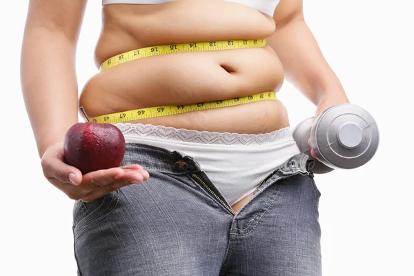 Fat woman with unzup jeans holding apple and weight on each hand — Stock Photo, Image