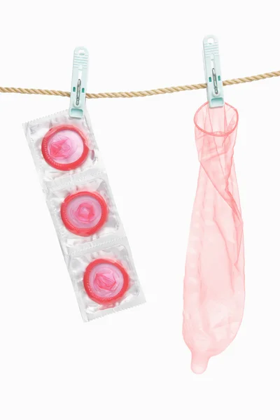 Kondom visí nad bílým pozadím — Stock fotografie