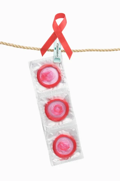 Condom hanging with red ribbon over white background — Stock Photo, Image