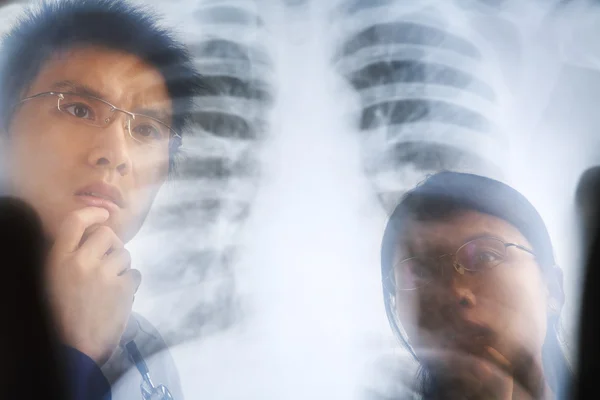 Asiático médico examinando raio-x negativo — Fotografia de Stock