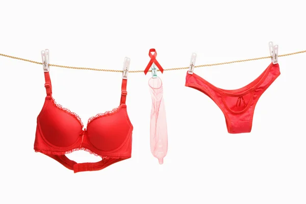 Roupa interior vermelha, fita e preservativos pendurados na corda — Fotografia de Stock