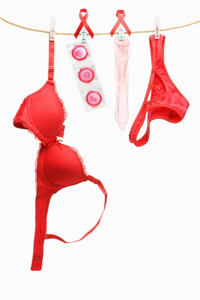 Roupa interior vermelha, fita e preservativos pendurados na corda — Fotografia de Stock