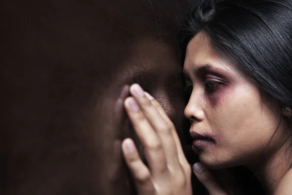 Mujer herida apoyada tristemente en la pared de madera — Foto de Stock