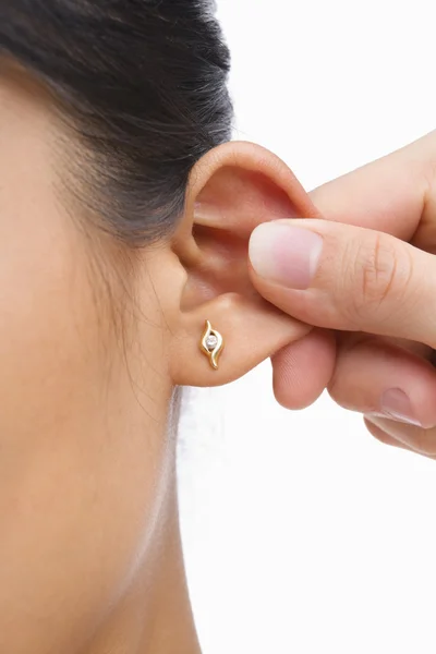 Finger pinching woman's ear — Stock Photo, Image