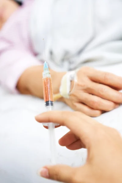 Ruka držící injekci rukou pacienta na pozadí — Stock fotografie