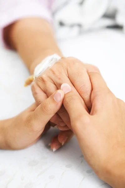 Дочь держит мать за руку в больнице — стоковое фото