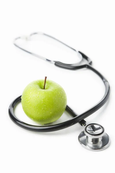 Estetoscópio e maçã verde sobre branco — Fotografia de Stock