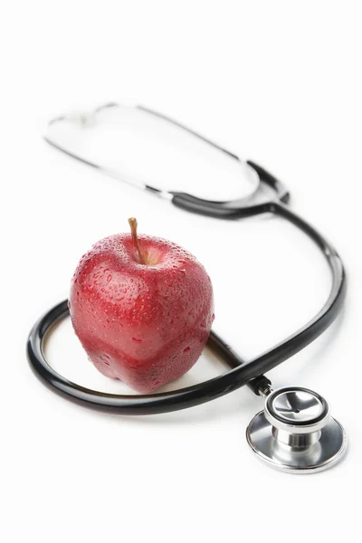 Stethoskop und roter Apfel über weißem — Stockfoto