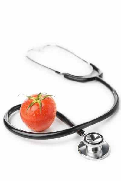 Estetoscópio e tomate sobre branco — Fotografia de Stock