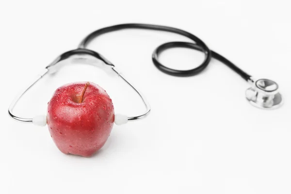 Красное яблоко в стетоскопе поверх белого — стоковое фото