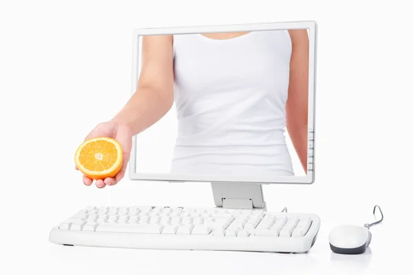Женщина держит оранжевый, выходящий с экрана компьютера — стоковое фото