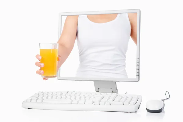 Female hand holding orange juice coming out from computer screen — Stock Photo, Image