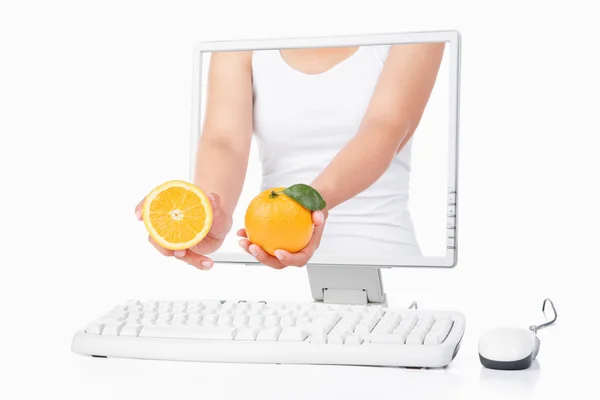 Mano femminile tenuta arancione che esce dallo schermo del computer — Foto Stock
