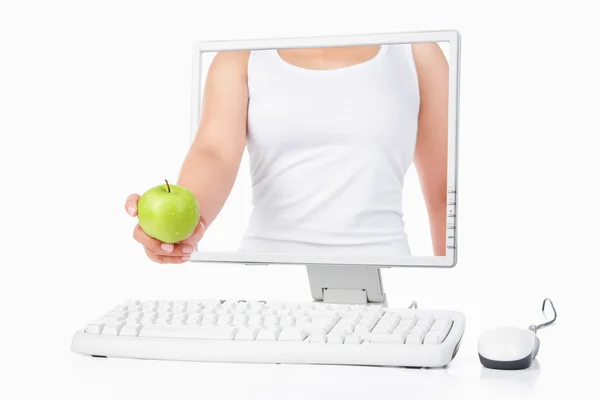 Female hand holding green apple coming out from computer screen — Stock Photo, Image
