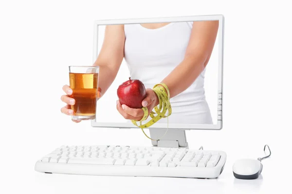 Женщина держит за руку красное яблоко, выходящее с экрана компьютера — стоковое фото