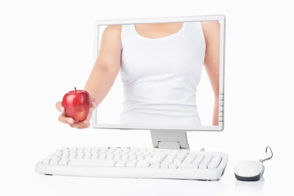 Жіноча рука тримає червоне яблуко, що виходить з екрану комп'ютера — стокове фото