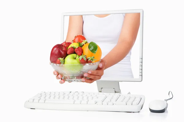 拿水果从电脑屏幕出来的女性手 — 图库照片