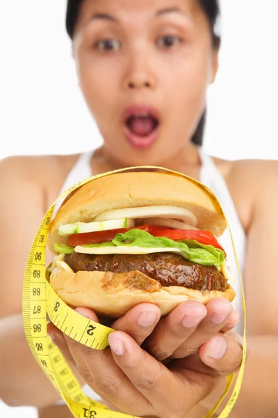Segurando hambúrguer com fita métrica ao redor — Fotografia de Stock
