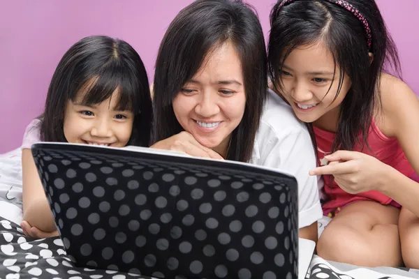 Mother and daughters playing with laptop — Stock Photo, Image