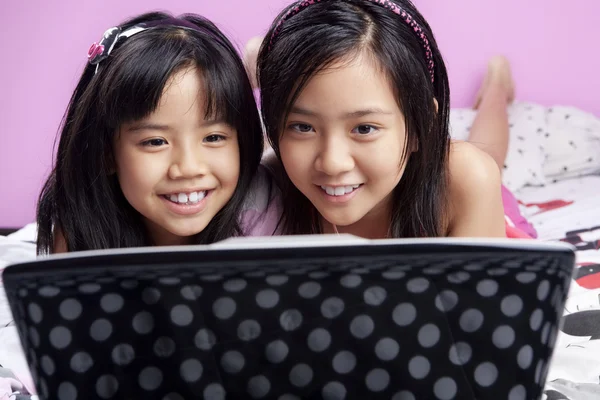 Две маленькие девочки играют с ноутбуком — стоковое фото