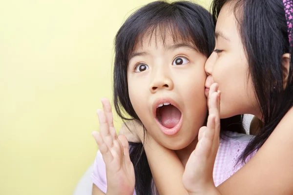 Девушка целует свою младшую сестру — стоковое фото