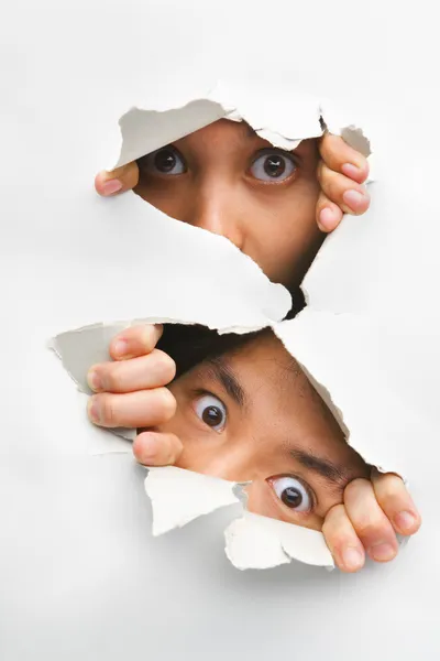 Two peeking from hole in wall — Stock Photo, Image