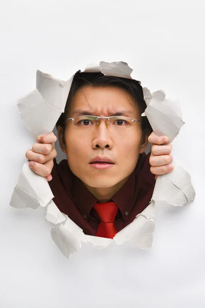 Man gazing seriously from hole in wall — Stock Photo, Image