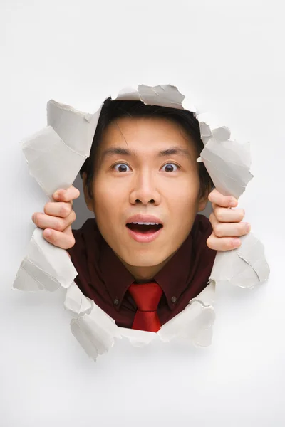 Man happily gazing from hole in wall — Stock Photo, Image
