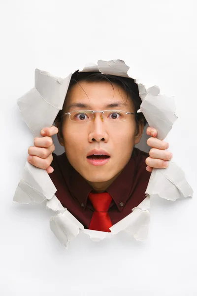 Man gazing surprisingly from hole in wall — Stock Photo, Image