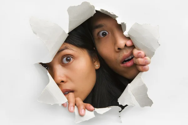 Two peeking from hole in wall — Stock Photo, Image