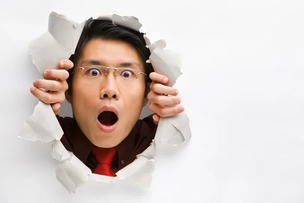 Man gazing surprisingly from hole in wall with copy space — Stock Photo, Image