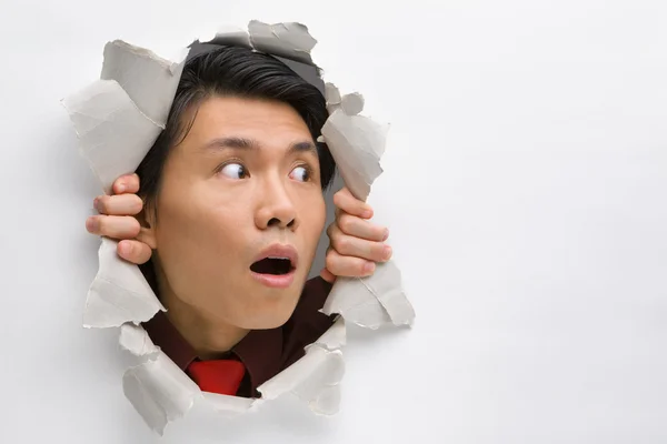 Man from hole in wall surprisingly looking away to his left side — Stock Photo, Image