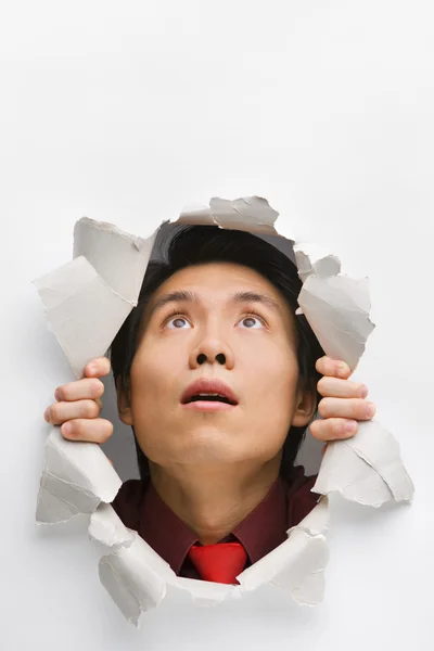 Man looking up surprisingly from hole in wall — Stock Photo, Image