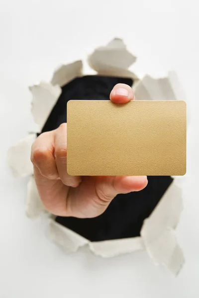 Hand breakthrough wall holding empty golden card — Stock Photo, Image