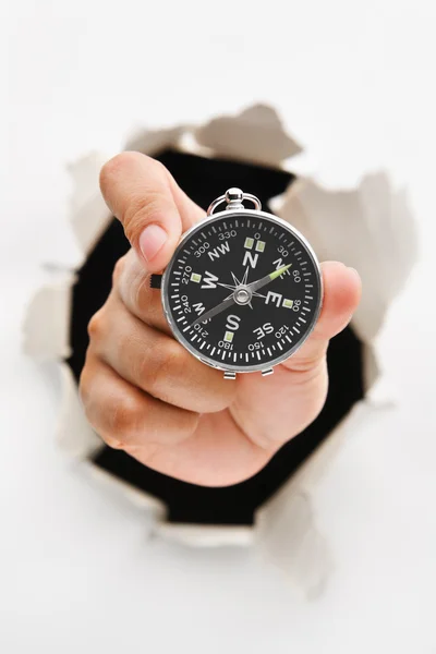 Hand breakthrough wall holding compass — Stock Photo, Image
